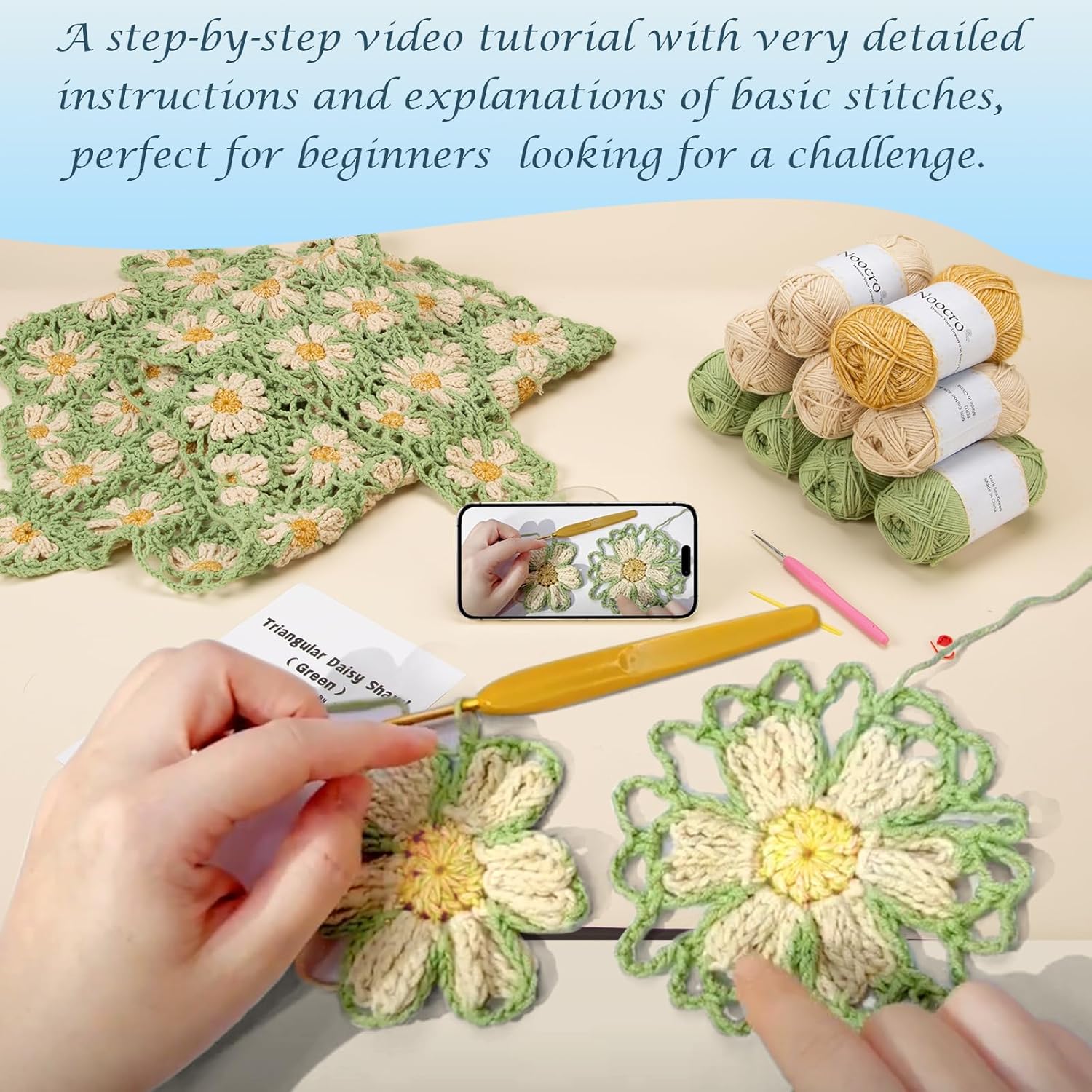 Hands crocheting daisy motifs with step-by-step video tutorial on phone, showing yarn and half-finished green shawl